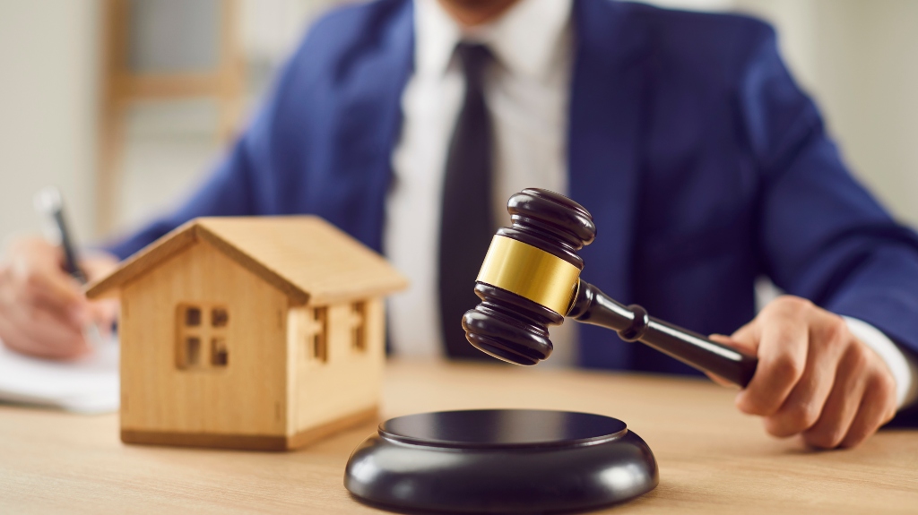 Male judge sitting at desk with gavel and small wooden toy house