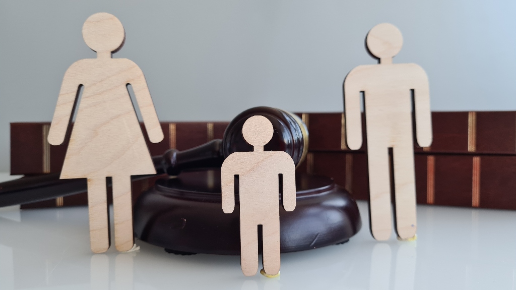 Wooden figures representing a family near a judge's gavel