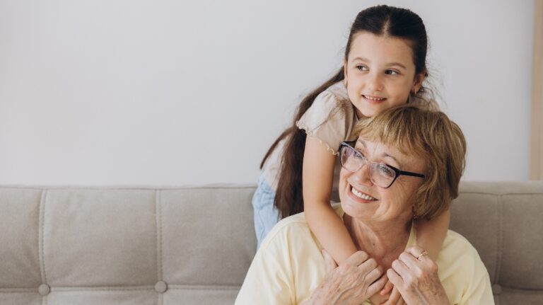 Cheerful cute granddaughter kid and happy grandma hugging with love, tenderness, affection, Grandmother embracing grandchild, enjoying family relationship.