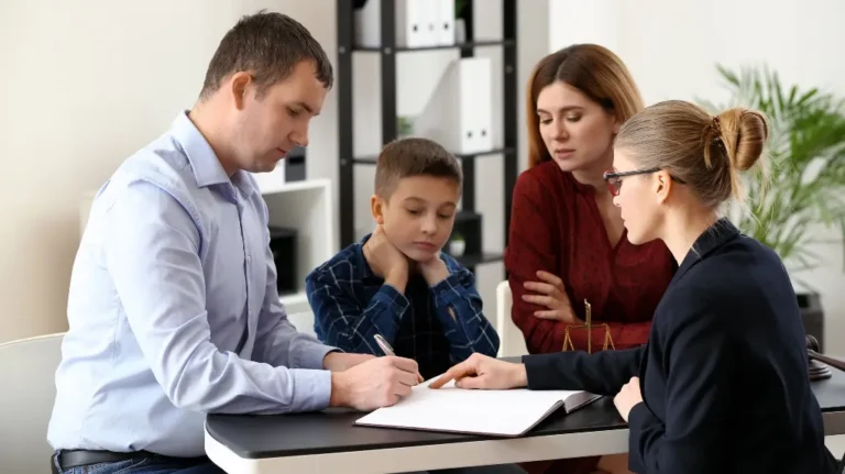 Professional woman explaining documents to a family of three at an office desk.