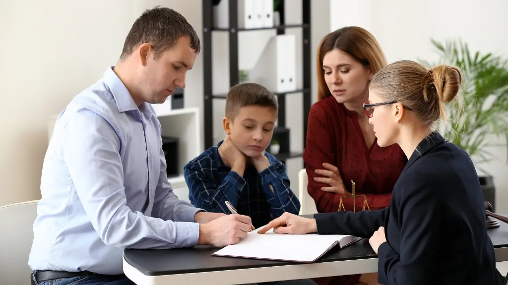 Professional woman explaining documents to a family of three at an office desk.